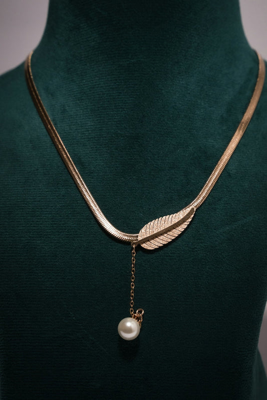 A green mannequin with a gold necklace and a pearl